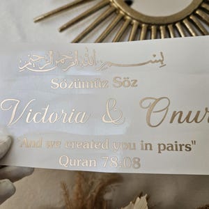 May include: A rectangular white decal sheet featuring gold metallic lettering. The text includes Arabic calligraphy, the words "S&ouml;z&uuml;m&uuml;z S&ouml;z", the names "Victoria & Onur", and the quote "And we created you in pairs" followed by "Quran 78:08".