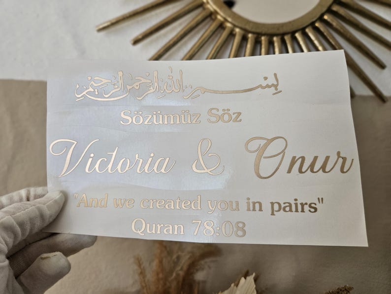 May include: A rectangular white decal sheet featuring gold metallic lettering. The text includes Arabic calligraphy, the words "S&ouml;z&uuml;m&uuml;z S&ouml;z", the names "Victoria & Onur", and the quote "And we created you in pairs" followed by "Quran 78:08".
