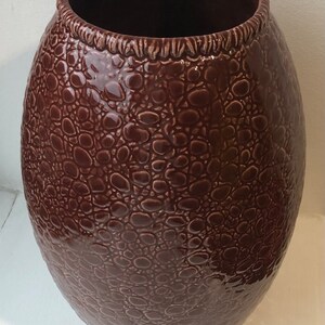 May include: A large, brown ceramic vase with a textured, alligator skin-like design.