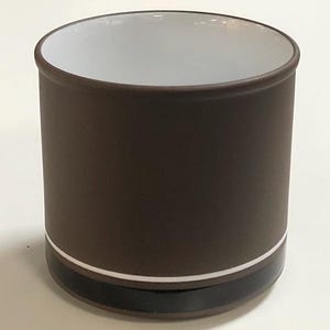 May include: A cylindrical brown ceramic container with a white interior. The container has a dark brown exterior with a white and black band near the base. The rim is also dark brown.