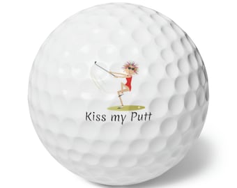 May include: White golf ball with a cartoon illustration of a woman playing golf and the text "Kiss my Putt".