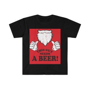 May include: Black t-shirt with a red square graphic featuring a cartoon beard, thumbs up, and the text "THIS GUY NEEDS A BEER!". The design has a distressed, vintage look.