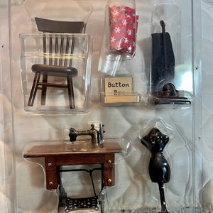 May include: A dollhouse accessory set featuring a wooden chair, a sewing machine, a mannequin, a vacuum cleaner, a button box, and a red and white patterned fabric.