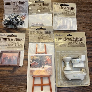 May include: A set of miniature dollhouse furniture, including a bathroom set, a framed picture, an easel with a painting, and a set of wine glasses. The packaging for each item features the Darice Timeless Minis logo and details about the product.