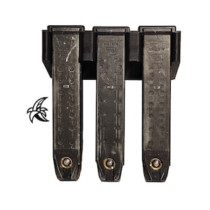 Puede incluir: Tres portacargadores negros con tres cargadores negros insertados. Los cargadores están etiquetados con "AUSTRIA" y "GLOCK".