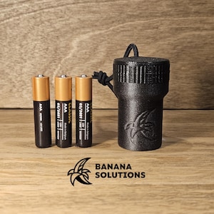 May include: Three AAA batteries with expiration dates of 03/2031 and a black plastic container with a banana logo and the text "BANANA SOLUTIONS".