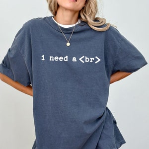 May include: A dark blue oversized t-shirt with the text "I need a <br>" printed in white.