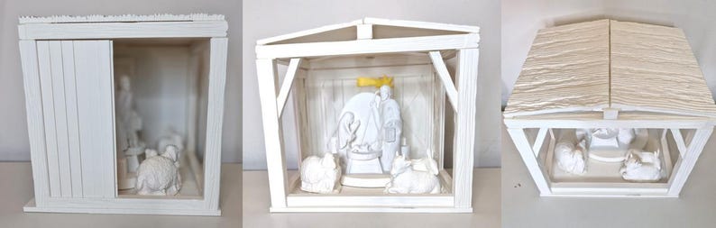 May include: A white wooden nativity scene with a pitched roof and a sliding door. Inside, white figurines depict the holy family and animals. The scene is set inside a small, open-fronted structure.
