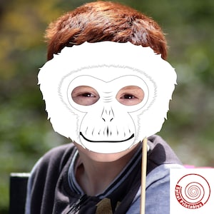 May include: A white paper mask of a monkey with a smiling expression. The mask is held up to a child's face.