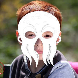 Peut inclure: Un masque en papier blanc d'une pieuvre avec de grands yeux et des tentacules. Le masque est port&eacute; par un enfant aux cheveux roux.
