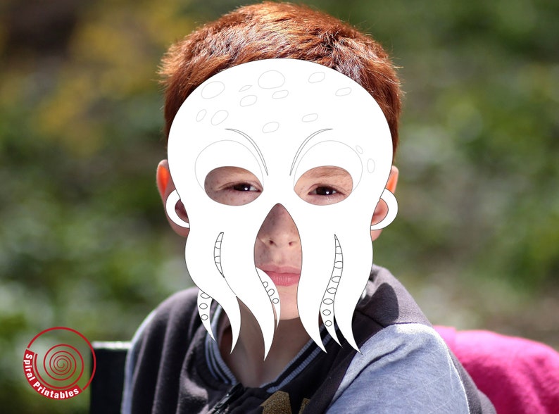 Peut inclure: Un masque en papier blanc d'une pieuvre avec de grands yeux et des tentacules. Le masque est port&eacute; par un enfant aux cheveux roux.