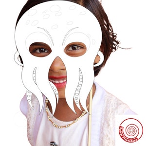 Peut inclure: Un masque d'octopus en papier blanc avec des trous pour les yeux et des tentacules. Le masque est tenu devant le visage d'un enfant. L'enfant sourit et porte une chemise blanche et un collier en or.