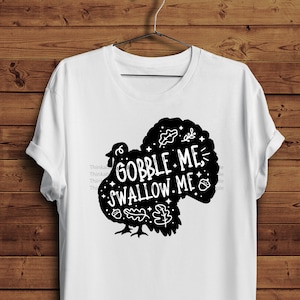 May include: White t-shirt featuring a black turkey graphic and the text "Gobble Me, Swallow Me".