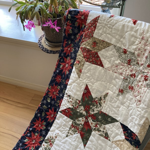 Poinsetta Stars a Christmas quilt to warm your holidays. Stars of cream, tan, red, sagy green and black prints float on an ivory backdrop.