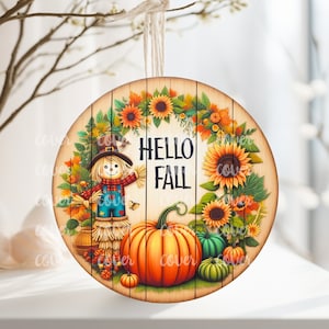 May include: Round wooden sign with a autumn theme. It features a scarecrow, pumpkins, sunflowers, and the text "Hello Fall".
