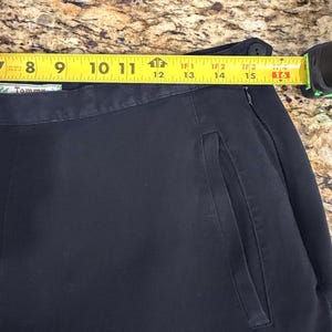 K&ouml;nnte beinhalten: Nahaufnahme einer marineblauen Hose mit einer Seitentasche. Ein gelbes Ma&szlig;band zeigt eine L&auml;nge von etwa 38 cm an. Die Hose ist dunkelblau.