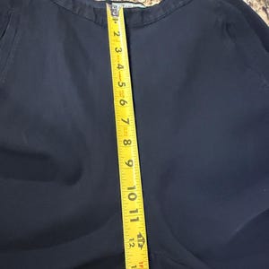 K&ouml;nnte beinhalten: Dunkelmarineblaue Hose mit einem gelben Ma&szlig;band, das eine L&auml;nge von etwa 35,5 cm anzeigt. Die Hose ist aus einem glatten Stoff gefertigt und scheint in gutem Zustand zu sein. Das Ma&szlig;band ist vertikal an der Hose positioniert.
