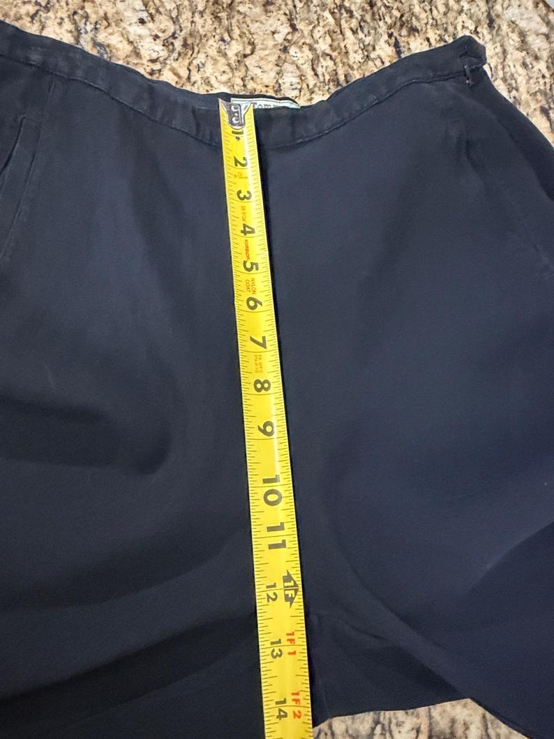 K&ouml;nnte beinhalten: Dunkelmarineblaue Hose mit einem gelben Ma&szlig;band, das eine L&auml;nge von etwa 35,5 cm anzeigt. Die Hose ist aus einem glatten Stoff gefertigt und scheint in gutem Zustand zu sein. Das Ma&szlig;band ist vertikal an der Hose positioniert.