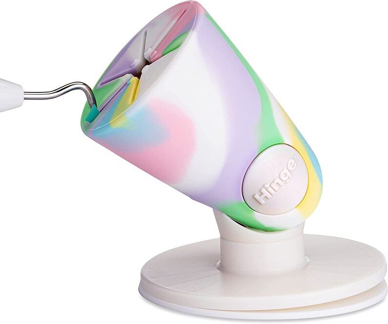 Puede incluir: Un soporte de tel&eacute;fono blanco con un dise&ntilde;o de remolino colorido y un bot&oacute;n blanco que dice "Hinge".