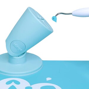 Puede incluir: Un soporte de ventosa azul claro, ajustable y giratorio, con la palabra "Hinge" impresa en &eacute;l. Una herramienta blanca con una punta azul se utiliza para aplicar una plantilla a una superficie azul claro.