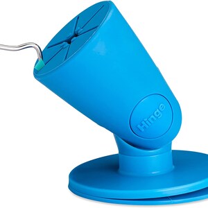 Puede incluir: Un soporte para tel&eacute;fono azul con una base giratoria y una bisagra. El soporte tiene una ventosa en la parte inferior y una ranura para sujetar un tel&eacute;fono.