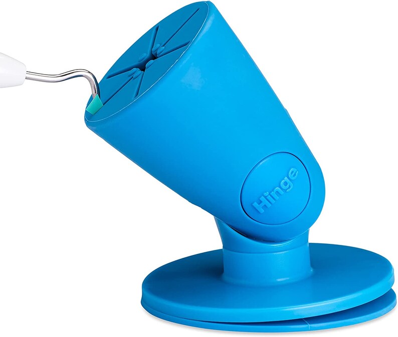 Puede incluir: Un soporte para tel&eacute;fono azul con una base giratoria y una bisagra. El soporte tiene una ventosa en la parte inferior y una ranura para sujetar un tel&eacute;fono.