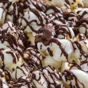 May include: Popcorn covered in white marshmallows and drizzled with melted dark chocolate.