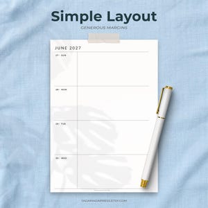 May include: A white paper planner page for June 2027 with a simple layout and generous margins, featuring horizontal lines for daily entries. A white pen with gold accents rests on the right side of the page. The text reads Simple Layout.