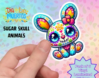 Könnte beinhalten: Ein farbenfroher Sugar-Skull-Hasen-Aufkleber mit floralem Design in leuchtenden Blau-, Rosa-, Gelb- und Orangetönen. Der Aufkleber ist Teil eines Sets mit sechs laminierten Vinyl-Aufklebern, mit dem Text "Dia de Los Muertos" und "Sugar Skull Animals".