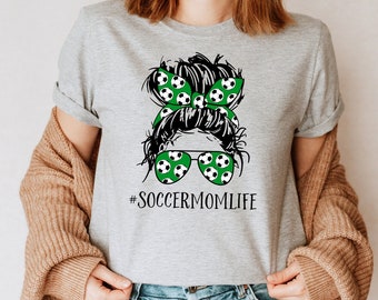 May include: Gray t-shirt with a graphic of a woman with a soccer ball headband and sunglasses. The text "#SOCCERMOMLIFE" is printed below the graphic.