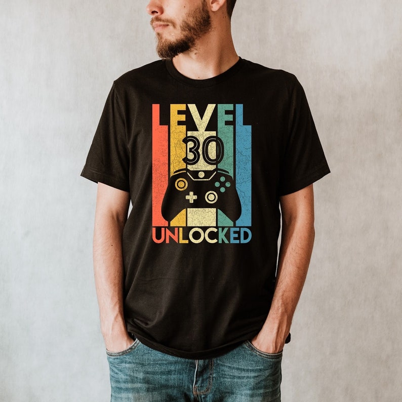 May include: A black t-shirt with a retro-style graphic that says "Level 30 Unlocked" with a colorful video game controller graphic.
