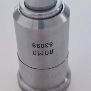 May include: A silver microscope objective lens with the text "OWOU 83066" printed on the side.