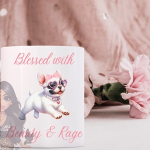 May include: White ceramic mug with a pink and white illustration of a French bulldog wearing heart-shaped sunglasses and a pink bow. The text "Blessed with Beauty & Rage" is printed on the mug.
