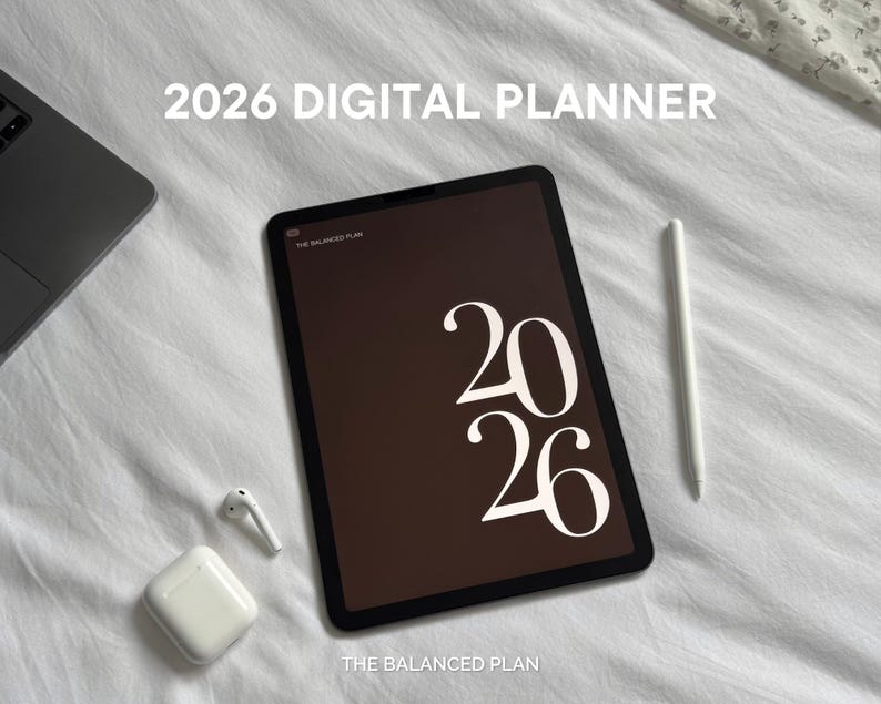 May include: A digital planner for 2026 displayed on a tablet with a stylus, earbuds, and a laptop. The tablet screen shows the numbers "2026" in white against a brown background. The text "THE BALANCED PLAN" is also visible.