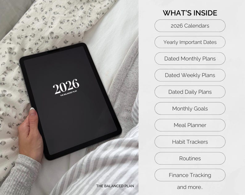 May include: A black tablet displaying the year 2026 in white text, with the words "THE BALANCED PLAN" below. The image also lists features such as calendars, monthly plans, and habit trackers. The tablet is held on a bed with a floral patterned sheet.