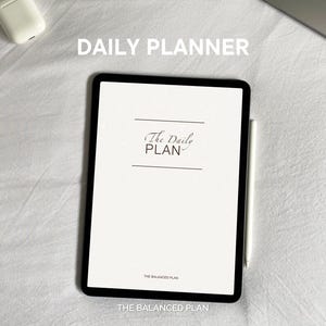May include: A white digital tablet with a black frame and a stylus. The screen displays the text "The Daily PLAN" and "THE BALANCED PLAN". The text "DAILY PLANNER" is displayed above the tablet.