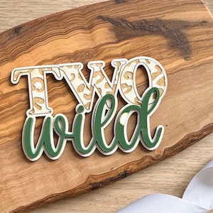 May include: Two Wild cake topper with the number two in a leopard print design and the word wild in green.