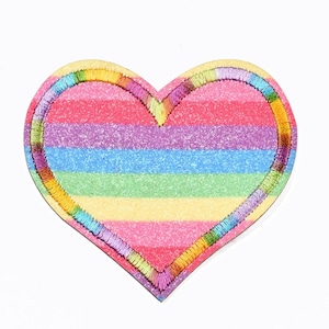 May include: A rainbow striped heart-shaped patch with a glittery finish. The heart is outlined with colorful embroidery.