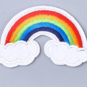 May include: A colorful rainbow with white clouds embroidered on a white fabric patch.