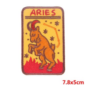 May include: A yellow and red embroidered iron-on patch with the zodiac sign Aries. The patch features a ram with a red and orange body and a brown face. The text "Aries" is embroidered in red on the patch. The patch measures 7.8 by 5 centimeters.
