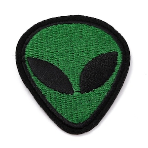 May include: Embroidered patch featuring a green alien head with black eyes and a black border. The patch has a textured appearance, and the alien design is centered on a white background. Ideal for jackets, bags, or other fabric items.