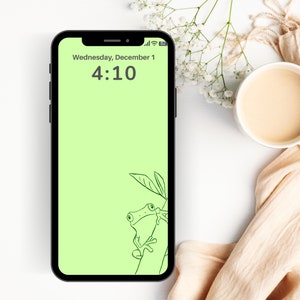 May include: A green phone screen with a light green background. The time is 4:10 and the date is Wednesday, December 1. A line drawing of a frog sitting on a branch is in the bottom right corner.