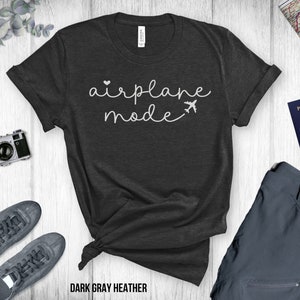 Puede incluir: Camiseta de color gris oscuro jaspeado con el texto "airplane mode" en escritura blanca con un peque&ntilde;o coraz&oacute;n y un gr&aacute;fico de avi&oacute;n.