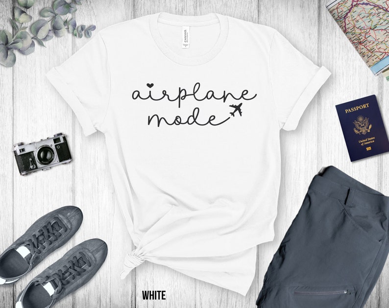 Puede incluir: Camiseta blanca con el texto "airplane mode" en escritura negra con un peque&ntilde;o coraz&oacute;n y un icono de avi&oacute;n.