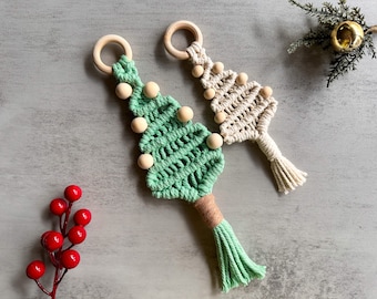 May include: Two handmade macrame Christmas tree ornaments with wooden beads. One ornament is green and the other is white.