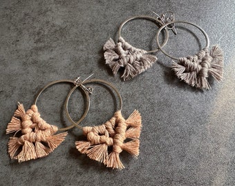 May include: Two pairs of hoop earrings with macrame fringe. One pair is beige and the other is gray.