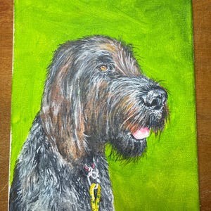 May include: A painting of a dog with a black and brown coat, looking to the right. The dog has a pink tongue sticking out and is wearing a collar with a yellow leash. The painting is on a green background and signed "Bob Hines".