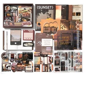 Op de afbeelding: Een briefpapier set met een verzameling papieren ephemera, stickers en kaarten met zonsondergang- en reisthema's. De items bevatten diverse rechthoekige prints, labels met tekst zoals Always on the Road en een doos met kleine decoratieve papieren stukjes.