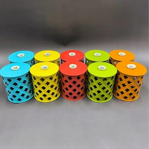 May include: A set of ten cylindrical metal containers arranged in two rows. Each container features a lattice-style cutout pattern, a solid circular top with a small white center hole, and comes in vibrant colors including blue, yellow, red, green, and orange.