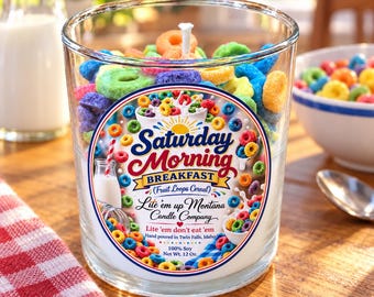 Könnte beinhalten: Eine durchsichtige Glaskerze gefüllt mit bunten ringförmigen Wachsstücken, die an Frühstücksflocken erinnern. Das Etikett zeigt Saturday Morning BREAKFAST (Fruit Loops Cereal) Lite 'em up Montana Candle Company Lite 'em don't eat 'em 100% Soy 340g.